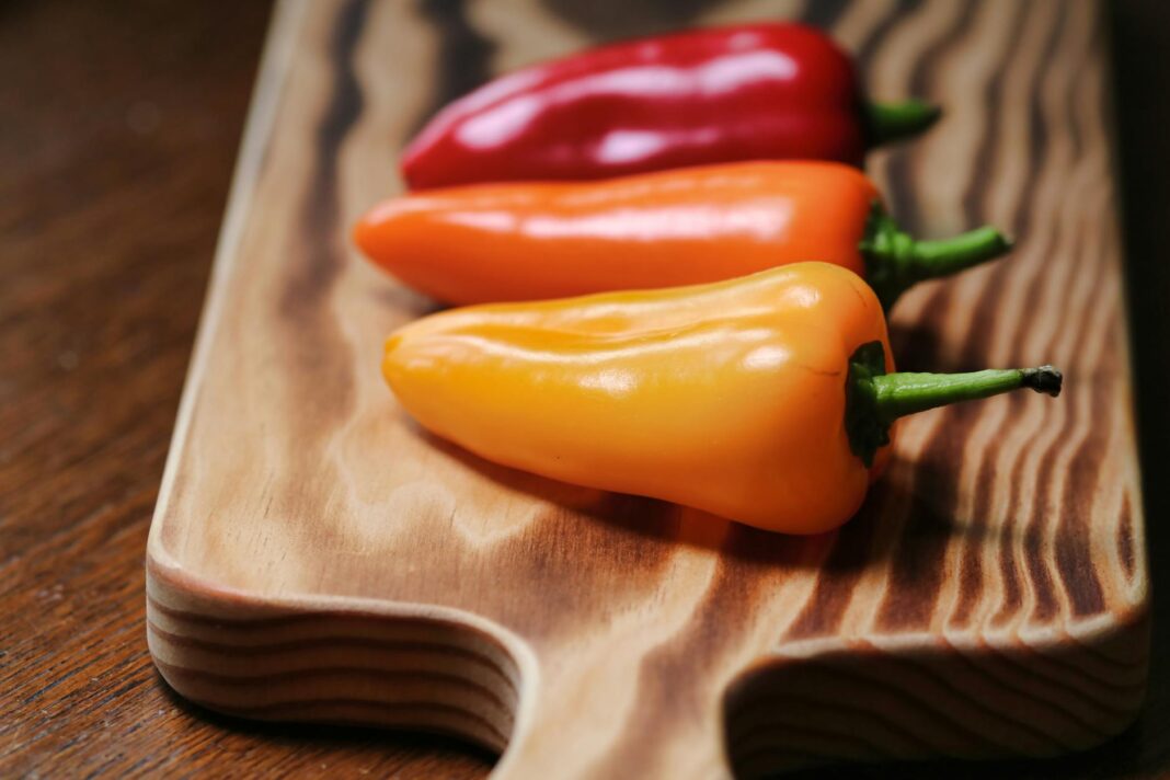 Colorful sweet peppers on a wooden board, showcasing freshness and healthy eating.