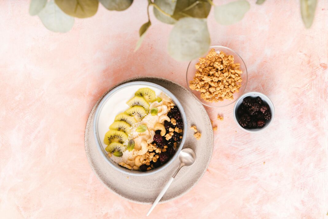 Top view of a healthy breakfast bowl with kiwi, granola, and blackberries.