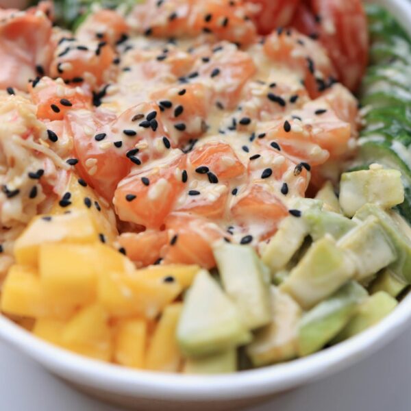 Delicious poke bowl featuring fresh salmon, avocado, mango, and sesame seeds.