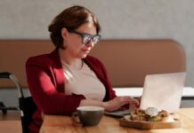 How To Lose 11 Pounds in 28 Days Using Quantum Nutrition Principles Woman in a red blazer working on laptop at café table with coffee and snack.