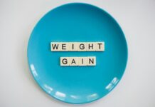 How To Reduce EMF-Related Weight Gain in 42 Days with Protective Foods Scrabble tiles spelling 'weight gain' on a blue plate, symbolizing health and diet.